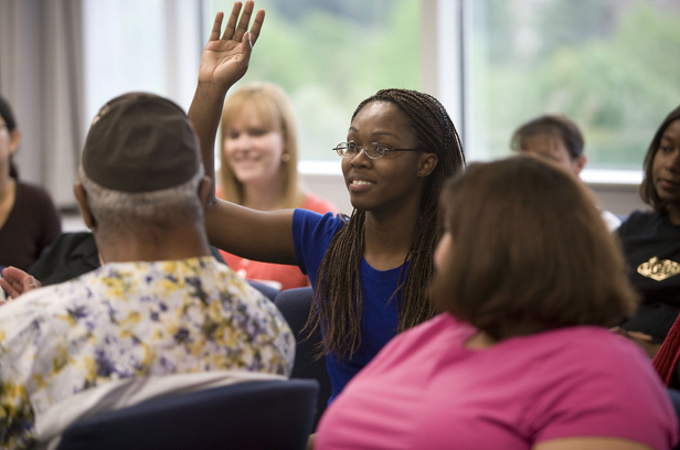 A woman raises her hand in a group setting