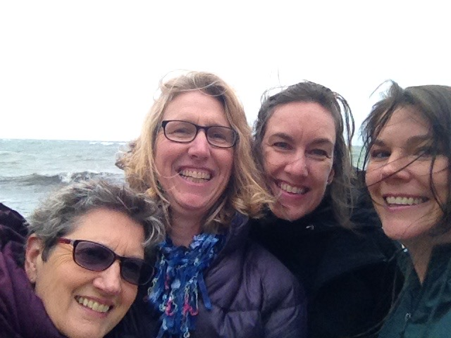 Four people pose for a selfie in front of the ocean.